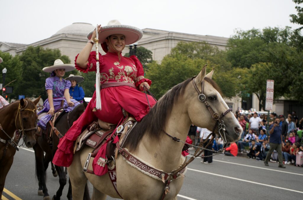 Woman in red charro dress riding horse