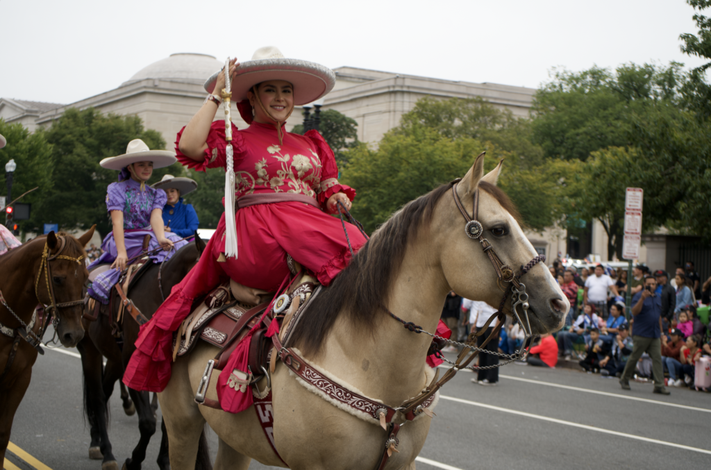 Woman in red charro dress riding horse