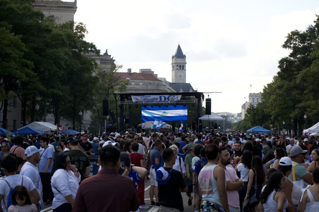 Festival al aire libre con mucho mundo, con escenario y pantalla