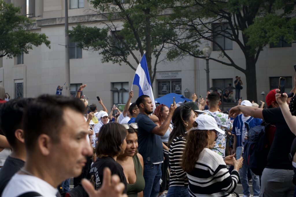 Multitud en una concentración al aire libre con una bandera azul y blanca