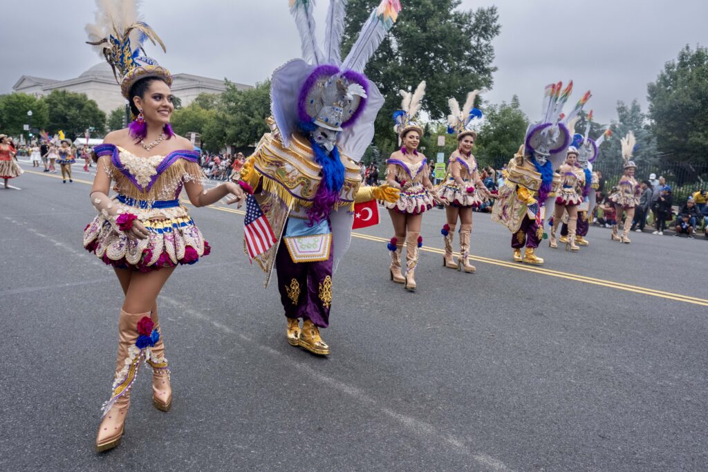 Dancers in colorful feathered costumes marching in parade