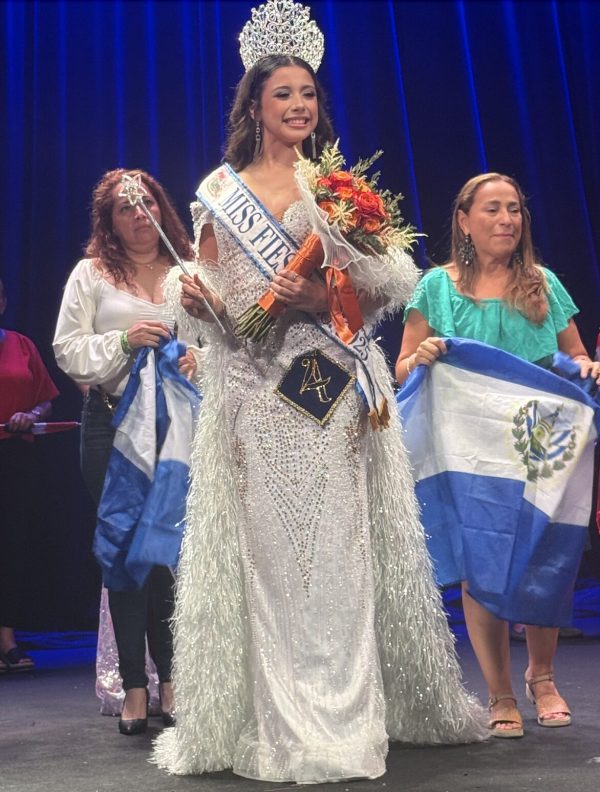 Crowned pageant winner onstage holding bouquet and sash